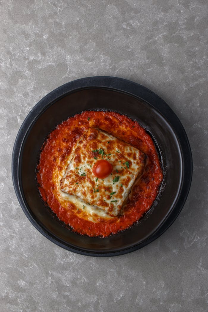 Mouth-watering Italian lasagna with creamy cheese topping in rich tomato sauce, perfect for food lovers.